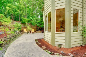 Walkout patio with sitting area and backyard leveled landscape design with stones. Tile walkway